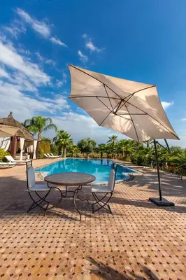 a table and chairs with an umbrella next to a pool at Ksar Salha in Marrakech
