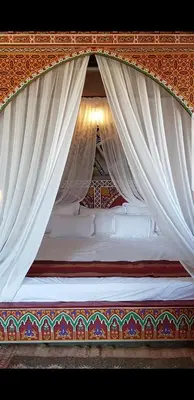 a canopy bed with white drapes on it at Ksar Salha in Marrakech