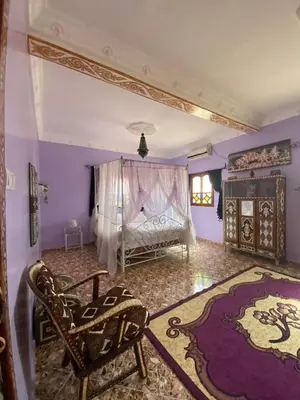 a bedroom with a bed and a chair and a rug at Dar Ilyana in Tamezmoute