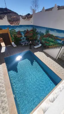 a large blue swimming pool in front of a building at Dar Ilyana in Tamezmoute