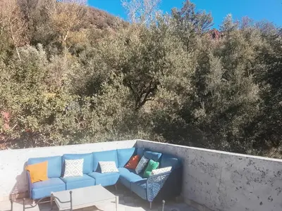 a blue couch with pillows on a wall with trees at Chez Yahia, Au coeur de L'Ourika in Ourika