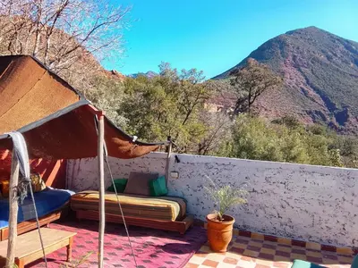 a bed on a balcony with a view of a mountain at Chez Yahia, Au coeur de L'Ourika in Ourika