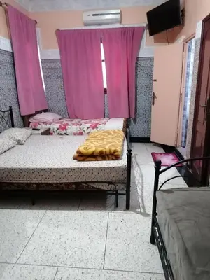 a bedroom with two beds and pink curtains at La Perle in Meknès