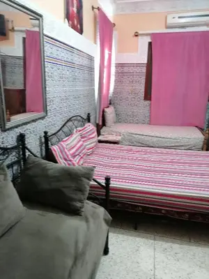 a room with two beds and a mirror and pink curtains at La Perle in Meknès