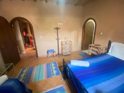a bedroom with a bed with blue sheets in a room at Riad Dar Barbara in Ouarzazate