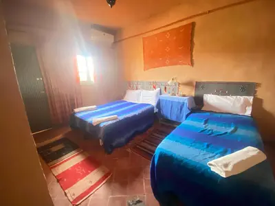 a room with two beds and a table in it at Riad Dar Barbara in Ouarzazate