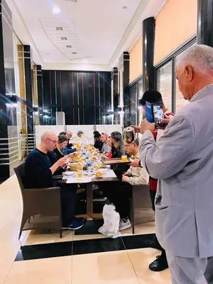 a man taking a picture of a group of people sitting around a table at Hotel La Luna in Beni Mellal
