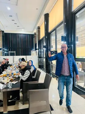 a man walking in a room with people sitting at tables at Hotel La Luna in Beni Mellal