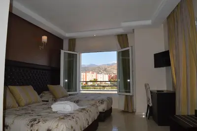 a bedroom with two beds and a large window at Hotel La Luna in Beni Mellal