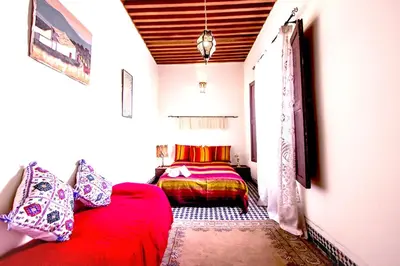 a bedroom with a red couch and a bed at Dar Nineta in Fès