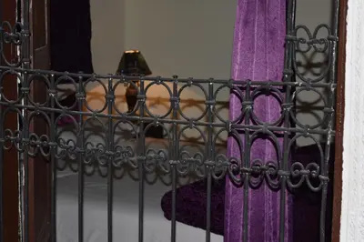 a iron gate on a bed with purple sheets at Dar Nineta in Fès