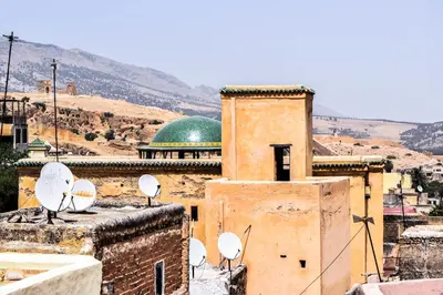 a building with satellites on top of it with a green dome at Dar Nineta in Fès