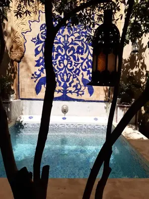 a swimming pool with a blue and white patterned wall at Les Bains de Fez Tara in Fès