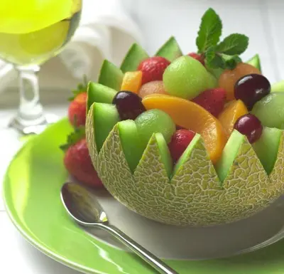 a bowl of fruit on a plate with a glass of wine at Hotel Arena Fes in Fès