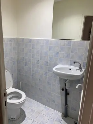 a blue tiled bathroom with a toilet and a sink at Appartement en plein centre ville in Fès