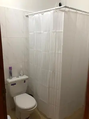 a bathroom with a toilet and a white shower curtain at Vittel Ifrane Large and Beautiful Apartment in Ifrane