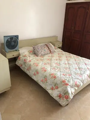 a bedroom with a bed with a floral comforter and a tv at Vittel Ifrane Large and Beautiful Apartment in Ifrane