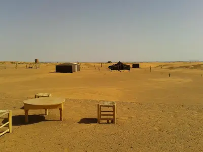 a table and chairs in the middle of a desert at Night Desert Camp in Merzouga