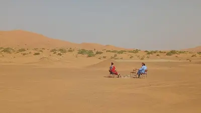two people sitting in chairs in the desert at Night Desert Camp in Merzouga
