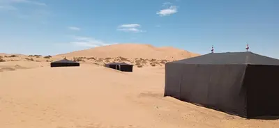 three buildings in the desert with a mountain in the background at Night Desert Camp in Merzouga