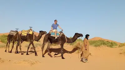 a man is riding a camel in the desert at Night Desert Camp in Merzouga