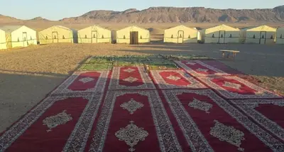 a large rug in the middle of a desert with tents at Bivouac Draa in Zagora