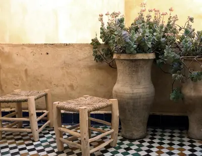 two stools and a large vase with plants in it at Dar Seffarine in Fès