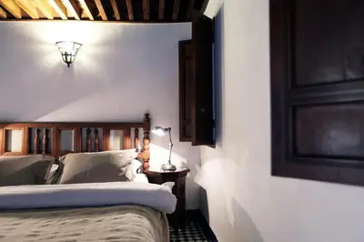 a bedroom with two beds and a lamp on a wall at Dar Seffarine in Fès