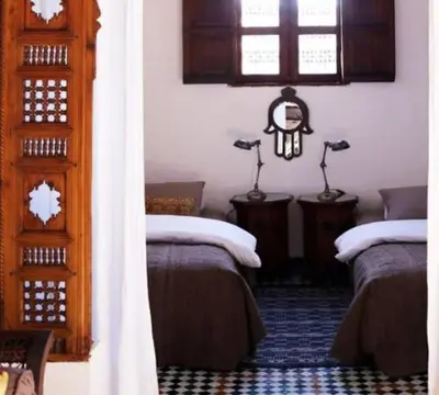 a room with two beds and two lamps on tables at Dar Seffarine in Fès