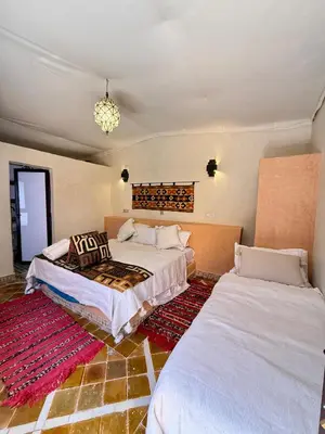 a bedroom with two beds and a chandelier at Royal Sands Camp - Erg Chigaga Luxury Camp in Mhamid