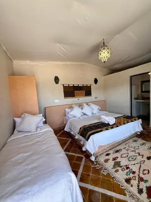 a bedroom with two beds and a chandelier at Royal Sands Camp - Erg Chigaga Luxury Camp in Mhamid