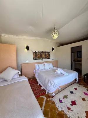 a bedroom with two beds and a chandelier at Royal Sands Camp - Erg Chigaga Luxury Camp in Mhamid