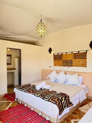 a bedroom with a large bed with a chandelier at Royal Sands Camp - Erg Chigaga Luxury Camp in Mhamid