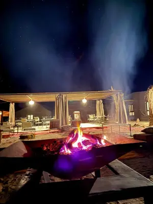 a fire pit at night with a building in the background at Royal Sands Camp - Erg Chigaga Luxury Camp in Mhamid