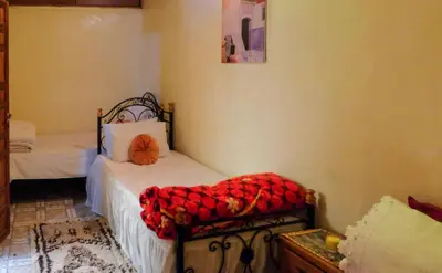 a bedroom with two beds and a bench with a red blanket at Dar Najia in Fès