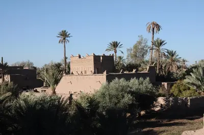 a building in the middle of a desert with palm trees at Gite Kasbah La Palmeraie in Skoura