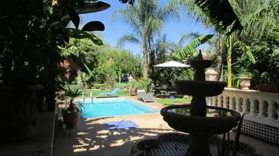 a swimming pool with a fountain in a yard at Villa La Zitoune in Aghmat