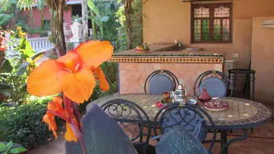 a table and chairs with a table and a flower at Villa La Zitoune in Aghmat
