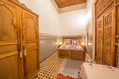 a bedroom with a bed and a wooden cabinet at Riad Ouliya in Fès
