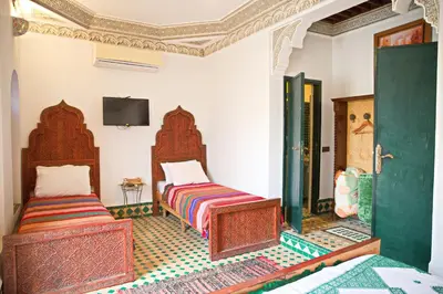 a bedroom with two beds and a tv on the wall at Riad Ouliya in Fès