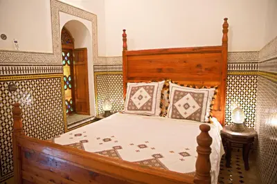 a bedroom with a large bed with a wooden headboard at Riad Ouliya in Fès