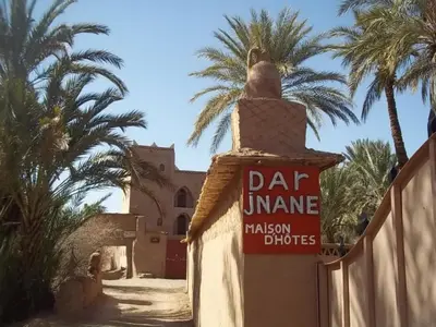 a sign on a fence in front of a building at Dar Jnane - La Maison Du Jardin in Agdz
