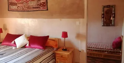 a bedroom with a bed with red pillows and a lamp at Dar Jnane - La Maison Du Jardin in Agdz
