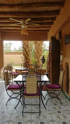 a table with chairs and a ceiling fan on a patio at Dar Jnane - La Maison Du Jardin in Agdz