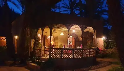 a house at night with a fence in front of it at Dar Jnane - La Maison Du Jardin in Agdz