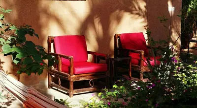 two red chairs sitting on a porch with flowers at Dar Jnane - La Maison Du Jardin in Agdz