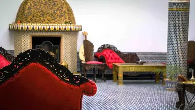 a living room with a red chair and a fireplace at Palais Nazha Fes - Luxury Lodging in Fès