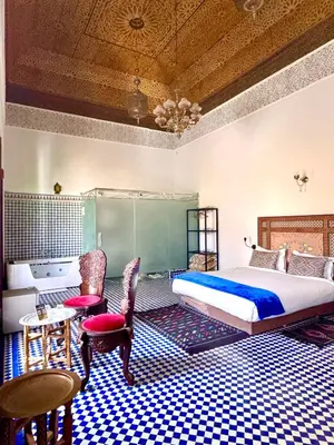 a bedroom with a bed and a table and chairs at Palais Nazha Fes - Luxury Lodging in Fès
