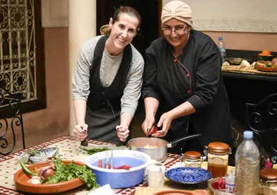 a man and woman standing in a kitchen preparing food at Palais Nazha Fes - Luxury Lodging in Fès
