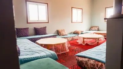 a living room with couches and tables and windows at Ouarzazate Youth Hostel YHO in Ouarzazate